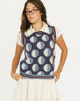 Woman wearing a patterned Yale Sweater Vest over a white shirt and skirt on a white background