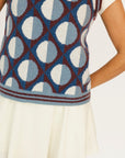 Woman wearing a patterned Yale Sweater Vest over a white shirt and skirt on a white background