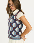 Woman wearing a patterned Yale Sweater Vest over a white shirt and skirt on a white background
