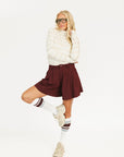 Woman wearing an angora and white Lottie Mock Neck with the Eleanor short in merlot.