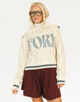 Person wearing a cream hoodie with 'FORE' text and maroon shorts on a white background