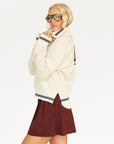 Person wearing a cream hoodie with 'FORE' text and maroon shorts on a white background