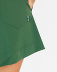 Person wearing a smoke blue sleeveless Annie Polo and a green Eleanor short on a plain background