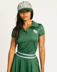 Woman wearing a green Brooklyn Polo and Brooklyn Skirt and a University Hat with visible branding on a white background