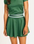 Person wearing a green Brooklyn skirt and polo on a white background. Featuring built in shorties and a Fore All logo on the front.