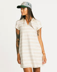 Woman wearing a Fore All Poppy white striped dress and cap on a plain background