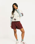 Woman wearing an angora Fore All Dillon Polo with various logos on a plain background