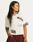 Woman wearing an angora Fore All Dillon Polo with various logos on a plain background
