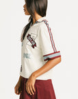 Woman wearing an angora Fore All Dillon Polo with various logos on a plain background