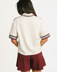 Woman wearing an angora Fore All Dillon Polo with various logos on a plain background