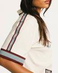 Woman wearing an angora Fore All Dillon Polo with various logos on a plain background