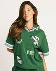 Woman wearing a green Fore All Dillon Polo with visible branding on a plain background