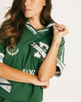 Woman wearing a green Fore All Dillon Polo with visible branding on a plain background