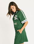 Woman wearing a green Fore All Dillon Polo with visible branding on a plain background