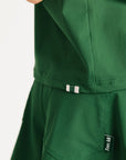 Woman wearing a green Fore All Dillon Polo with visible branding on a plain background