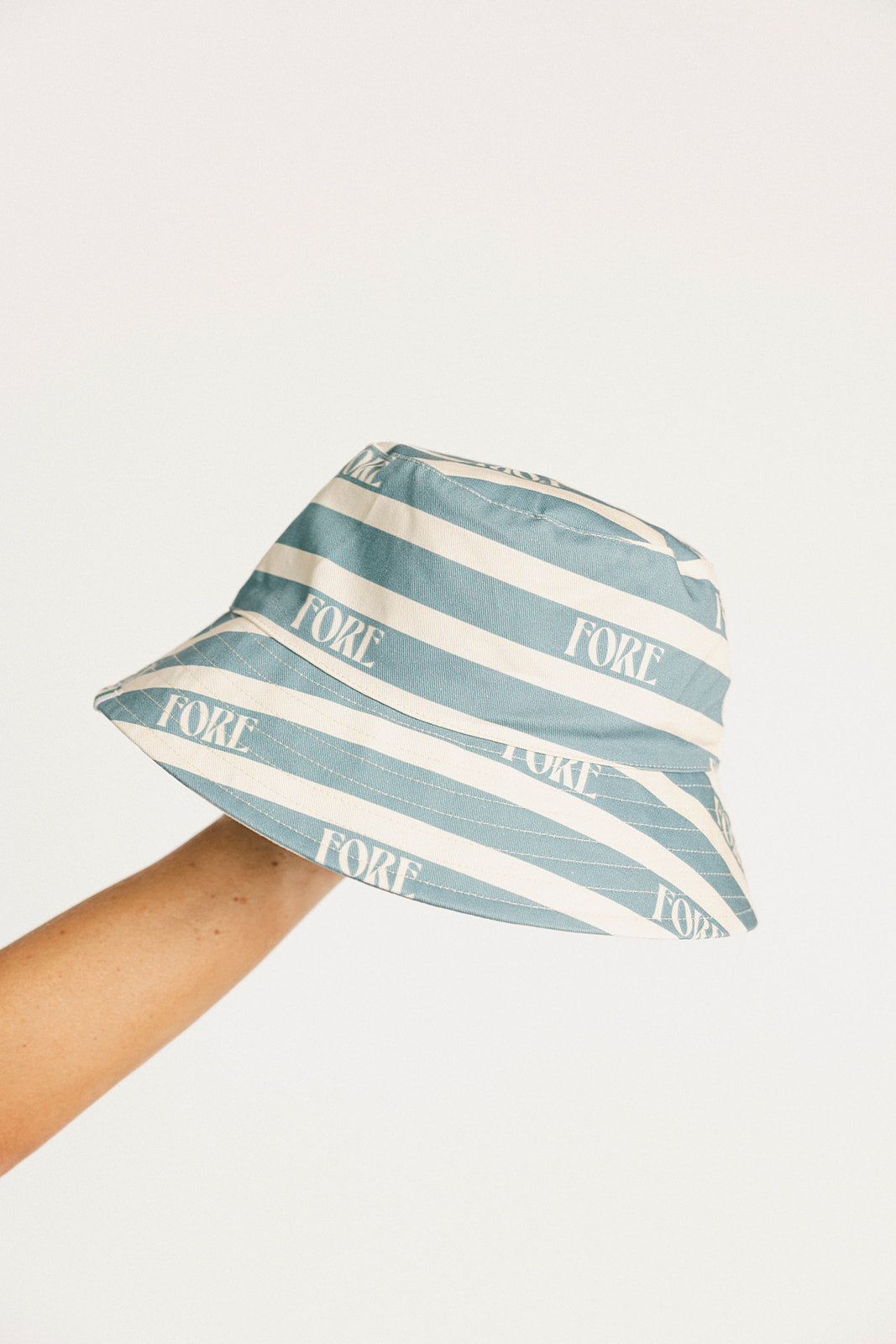 Blue and white striped bucket hat with 'FORE' branding on a light gray background