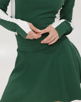A person wearing a high-waisted green skirt with a solid pattern and ribbed fabric.
