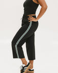 Person wearing black athletic outfit with white stripes on a white background
