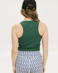 A woman wearing a green tank top with a built-in bra, paired with patterned shorts and a black cap with the text 'FORE ALL' on it.