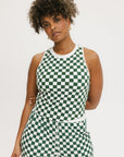 A woman wearing a green checkered tank top with a built-in bra, designed for golfing or casual wear.