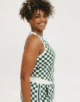 A woman wearing a green checkered tank top with a built-in bra, designed for golfing or casual wear.