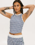 A woman wearing a blue geometric patterned tank top with a built-in bra, paired with matching pants.