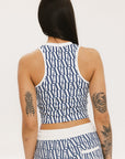 A woman wearing a blue geometric patterned tank top with a built-in bra, paired with matching pants.