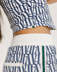 A woman wearing a blue geometric patterned tank top with a built-in bra, paired with matching pants.