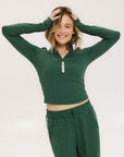 A woman wearing a green mock-neck long-sleeve golf top and matching pants.