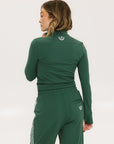 A woman wearing a green mock-neck long-sleeve golf top and matching pants.