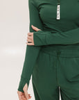 A woman wearing a green mock-neck long-sleeve golf top and matching pants.