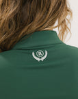 A woman wearing a green mock-neck long-sleeve golf top and matching pants.