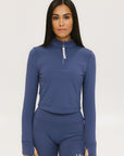 A woman wearing a blue mock-neck long-sleeve top and matching shorts with a golf logo on the shorts.