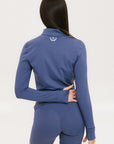 A woman wearing a blue mock-neck long-sleeve top and matching shorts with a golf logo on the shorts.