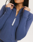 A woman wearing a blue mock-neck long-sleeve top.
