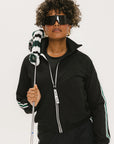 A person wearing a black jacket with green and white stripes on the sleeves
