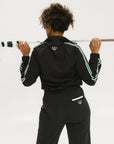 A person wearing a black jacket with green and white stripes on the sleeves