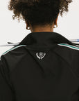 A person wearing a black jacket with green and white stripes on the sleeves