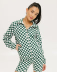 A woman is wearing a long sleeve jacket and shorts with a green and white checkered pattern.