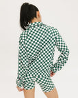 A woman is wearing a long sleeve jacket and shorts with a green and white checkered pattern.