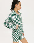 A woman is wearing a long sleeve jacket and shorts with a green and white checkered pattern.