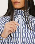 A woman wearing a long sleeve golf jacket with a pattern of blues and whites.