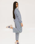 A person standing wearing the Bronson Pant in indigo color, which features a geometric pattern. The pants are casual and the person is paired them with a matching top and pink sneakers.
