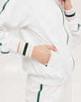 A woman wearing a white long sleeve golf jacket with green accents and a matching visor.