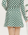 A person wearing a green and white checkered skirt with a matching long-sleeve top and sneakers, standing on a white background.