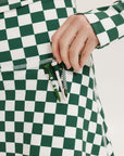 A person wearing a green and white checkered skirt with a matching long-sleeve top and sneakers, standing on a white background.