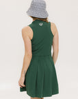 A woman in a green sleeveless knee-length dress with a top-to-bottom zipper, wearing a patterned hat.