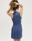 A woman in an indigo sleeveless knee-length dress with a top-to-bottom zipper.