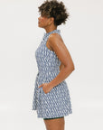 A model wearing a sleeveless blue and white geometric patterned dress with a zipper at the top, suitable for golf.