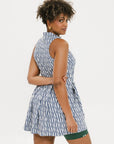 A model wearing a sleeveless blue and white geometric patterned dress with a zipper at the top, suitable for golf.